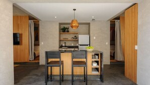 Une cuisine moderne dotée d’un îlot central, de deux tabourets de bar et d’un luminaire suspendu.