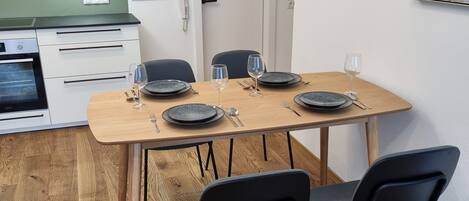 A modern kitchen with white cabinets, a wooden dining table set for four, and black chairs.