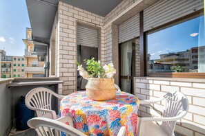 Un balcone con tavolo, sedie e un cesto di vimini con fiori.