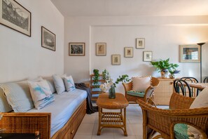 Une pièce comprenant un lit, un canapé, des meubles en osier et des tableaux encadrés accrochés au mur.