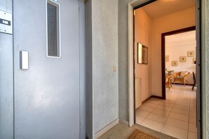 Un corridoio con una porta che dà su un soggiorno, con un divano e quadri appesi al muro.