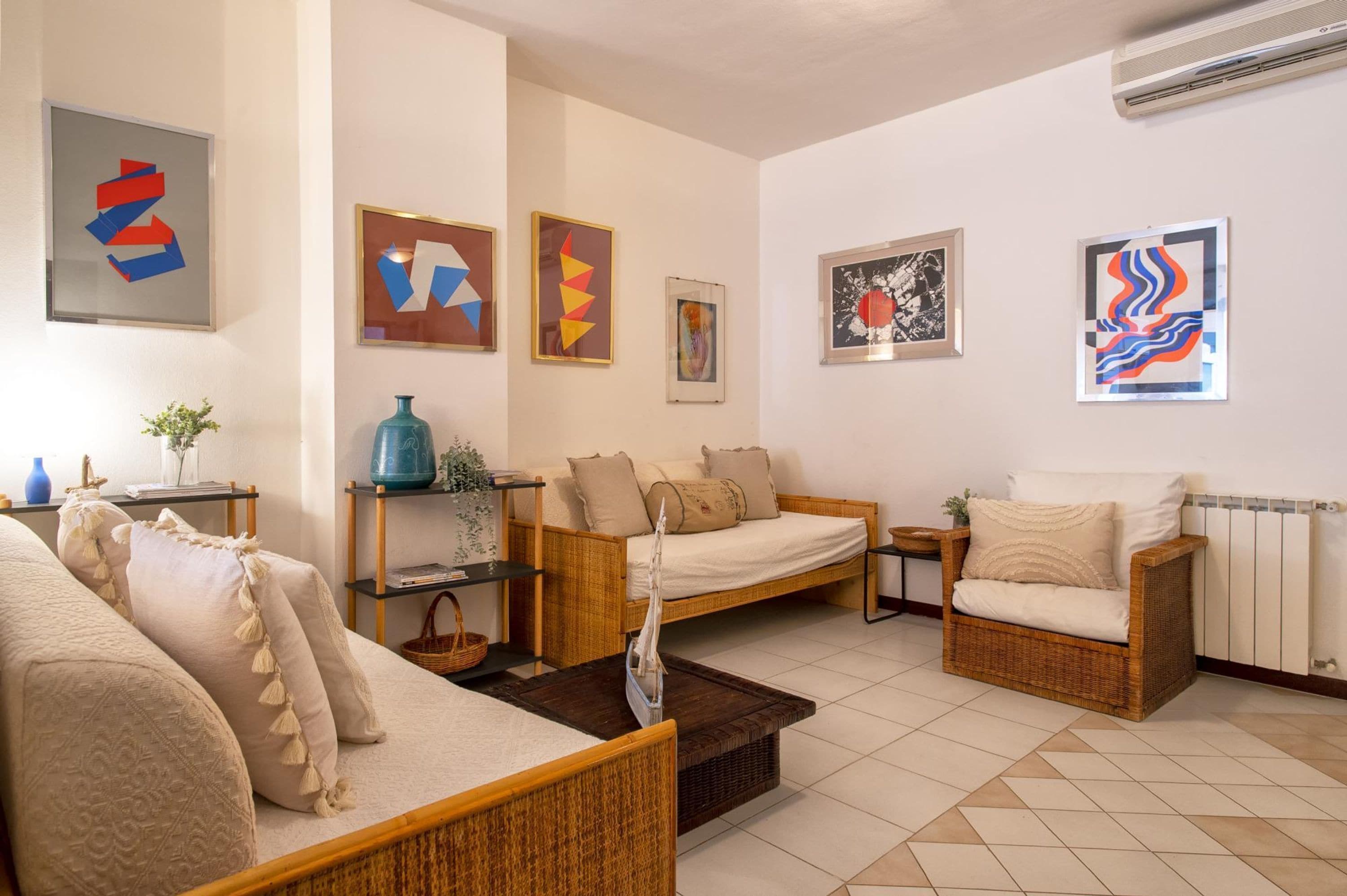 A living room with a sofa, two armchairs, a coffee table, and artwork on the walls.