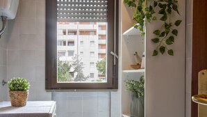 A bathroom with a window, a towel rack, a sink, and a shelf with plants.