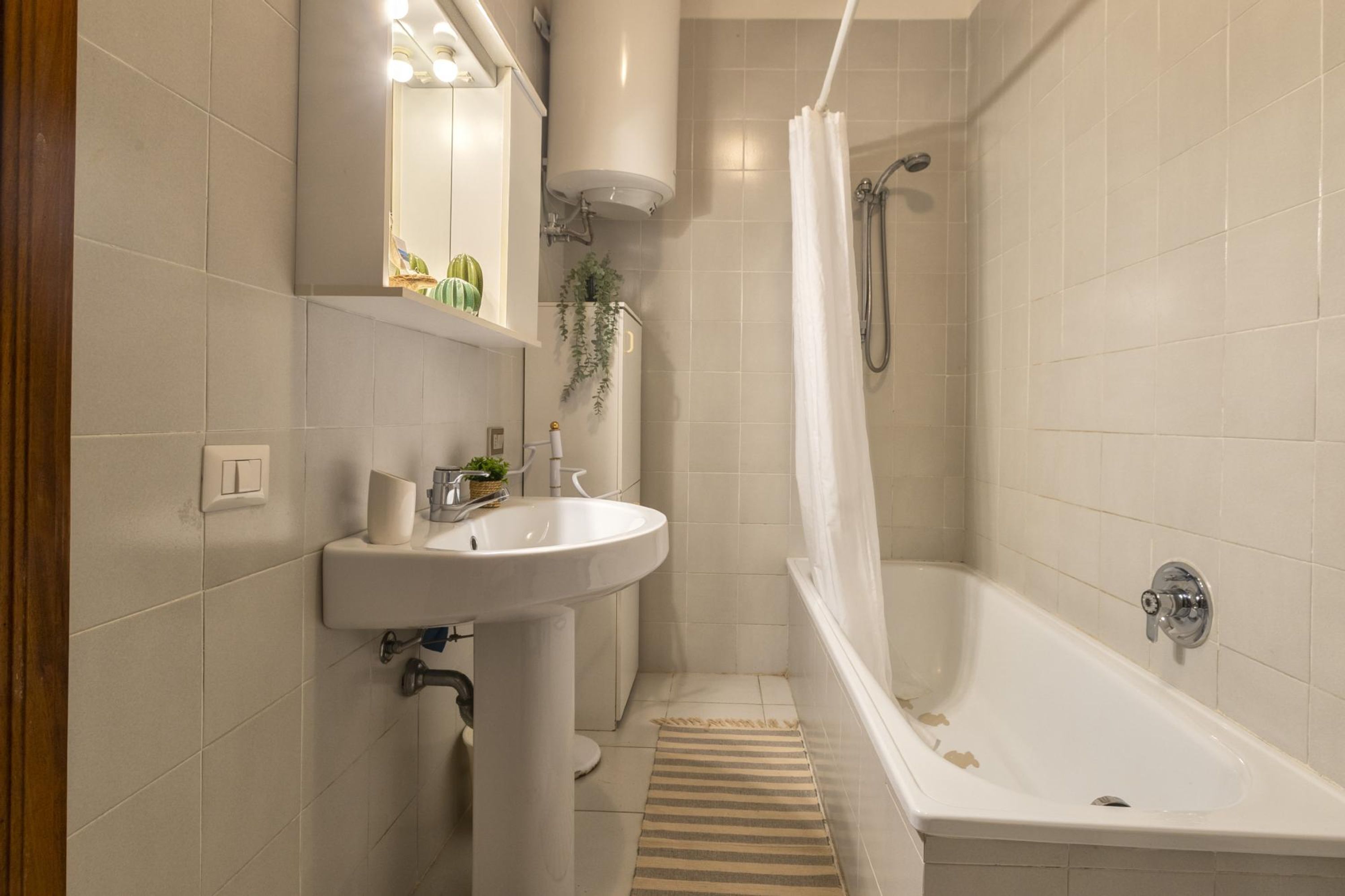A bathroom with a white sink, mirror, and shower.
