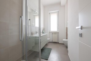 A modern bathroom with a glass shower enclosure, a white sink, and a toilet.