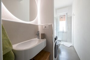 A modern bathroom with a white sink, a toilet, and a shower area.