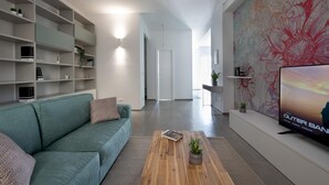 Un salon moderne avec un canapé de couleur turquoise, une table basse agrémentée d’une plante et un téléviseur posé sur un meuble.