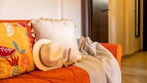 Ein gemütliches Zimmer mit einer Couch, einem Zierkissen und einem Hut.