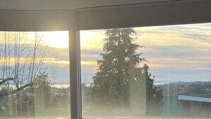 Ein Zimmer mit großem Fenster, einem Tisch mit Stühlen und einer Deckenleuchte.