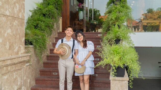 A couple standing on a staircase with greenery on either side. - SeaColor Beachstay Danang Hotel Haviland (Da Nang)