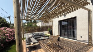 Eine moderne Außenpatio mit Holzdeck, einer eingebauten Sitzecke und einer großen Schiebeglastür.