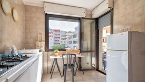 A modern kitchen with a dining area, a large window, and a view of a residential building. - Sardinia RE - Francesca s Flat - Free Parking (Alghero)