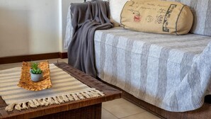 A cozy living room with a sofa, a bench, and a small potted plant. - Sardinia RE - Francesca s Flat - Free Parking (Alghero)