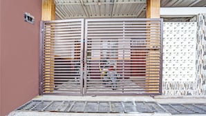 A metal gate with horizontal slats, a concrete floor, and a wall with a geometric pattern. - Hotel O Sobat Ijen HomestayNearSungai Prengsengan (Rogojampi)