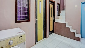 A laundry area with a washing machine, a staircase, and a door with a mirror. - Hotel O Sobat Ijen HomestayNearSungai Prengsengan (Rogojampi)