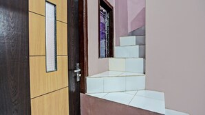 A staircase with white tiles leading to a landing, a wooden door with a glass panel, and a window with metal bars. - Hotel O Sobat Ijen HomestayNearSungai Prengsengan (Rogojampi)