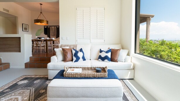 A modern living room with a white sofa, a coffee table, and a view of greenery through a window. - Hot Tub/Pool, Views, Pets-Catalina Foothills Casa (Tucson)