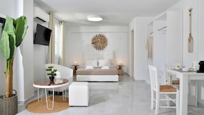 Een moderne slaapkamer met een bed, nachtkastjes, een klein rond tafeltje en een stoel.