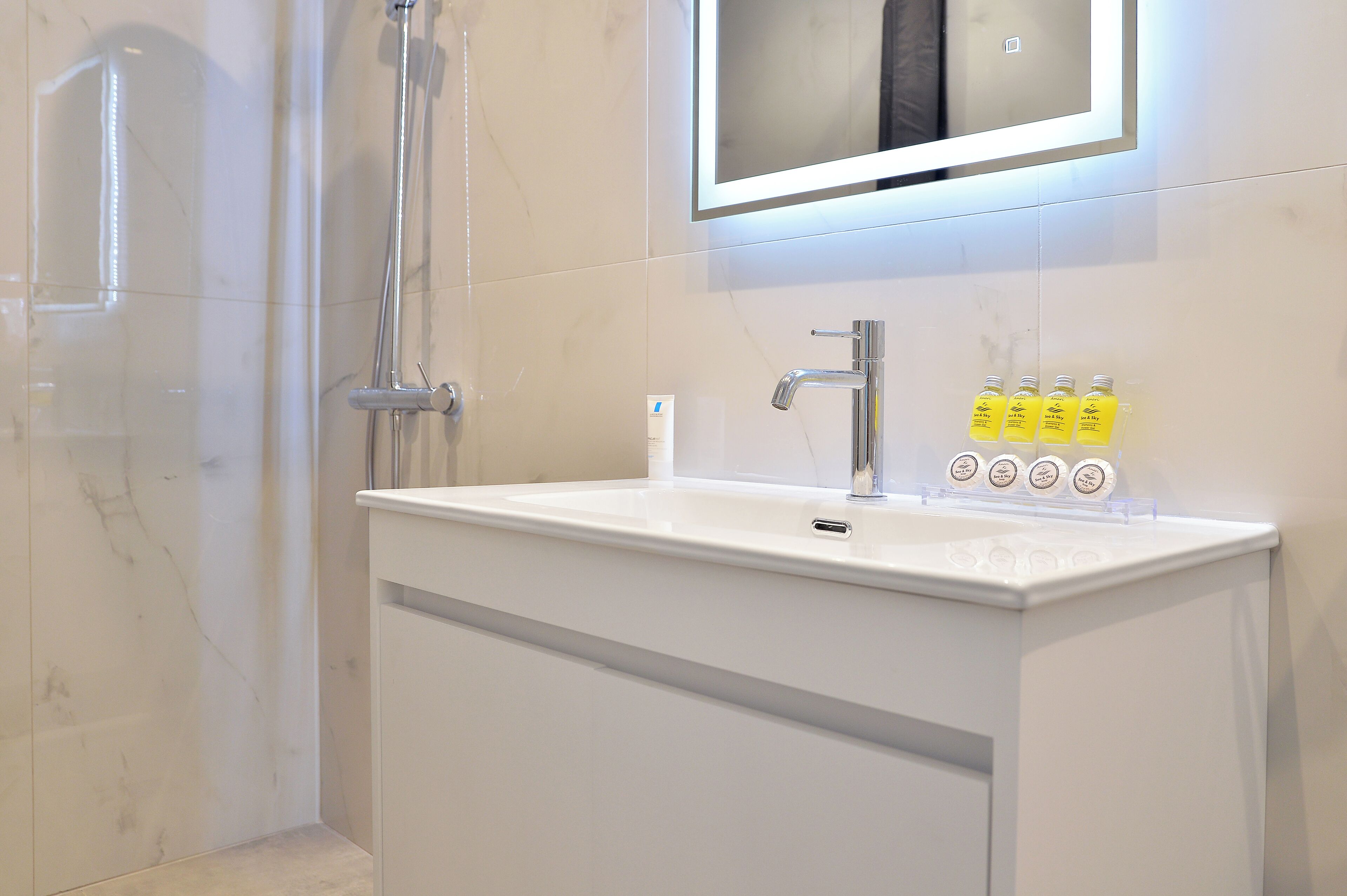 A bathroom with a white sink, a mirror above it, and a showerhead.