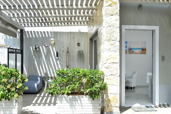 Relax in a tranquil outdoor space with a pergola, seating area, and lush greenery.