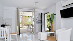 Een moderne woonkamer met een witte bank, een eethoek met een witte tafel en stoelen, en een glazen schuifdeur naar een terras.