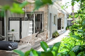 Relax in a serene outdoor space with two hammocks, a small table, and chairs, surrounded by lush greenery.