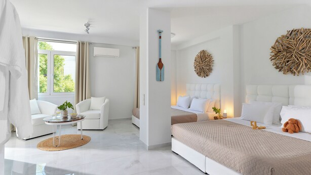 Een moderne slaapkamer met een groot bed, een zithoek met een witte bank en een kleine ronde tafel.