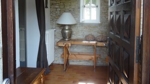 A hallway with a stone wall, a wooden bench, a table with a lamp, a door with a window, and a radiator. - Nyons ,villa au Cœur des Vignes et des Oliviers Avec Grande Piscine (Nyons)