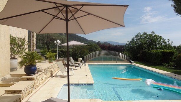 A swimming pool with lounge chairs and an umbrella, surrounded by stone walls and potted plants. - Nyons ,villa au Cœur des Vignes et des Oliviers Avec Grande Piscine (Nyons)