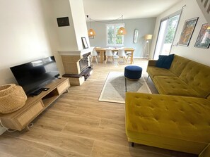 Un salon moderne doté d’un téléviseur à écran plat, d’une cheminée, d’un canapé jaune et d’un coin repas avec une table et des chaises.