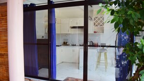 A modern kitchen with white cabinets, a marble backsplash, and a bar area with stools. - A's Place (Valencia)