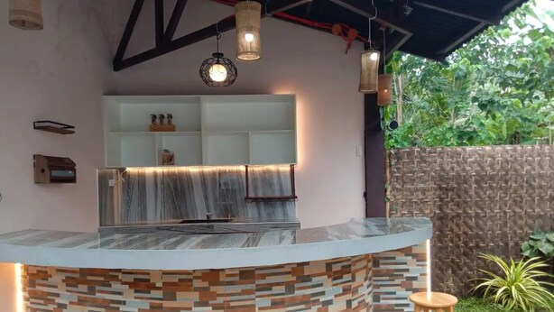 A modern kitchen with a marble countertop, wooden stools, and hanging lights. - A's Place (Valencia)