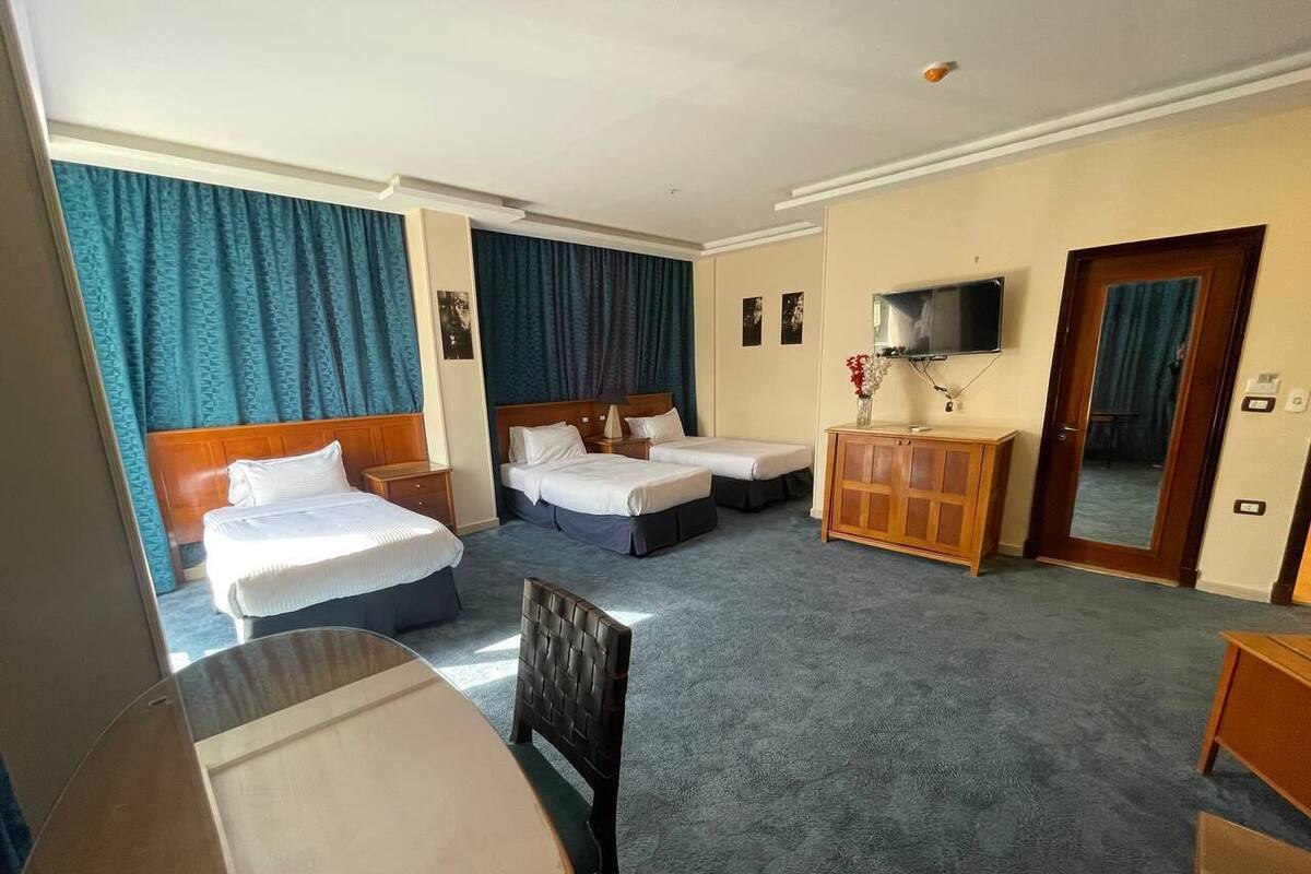 A hotel room with two beds, a TV, a desk, and a wardrobe.