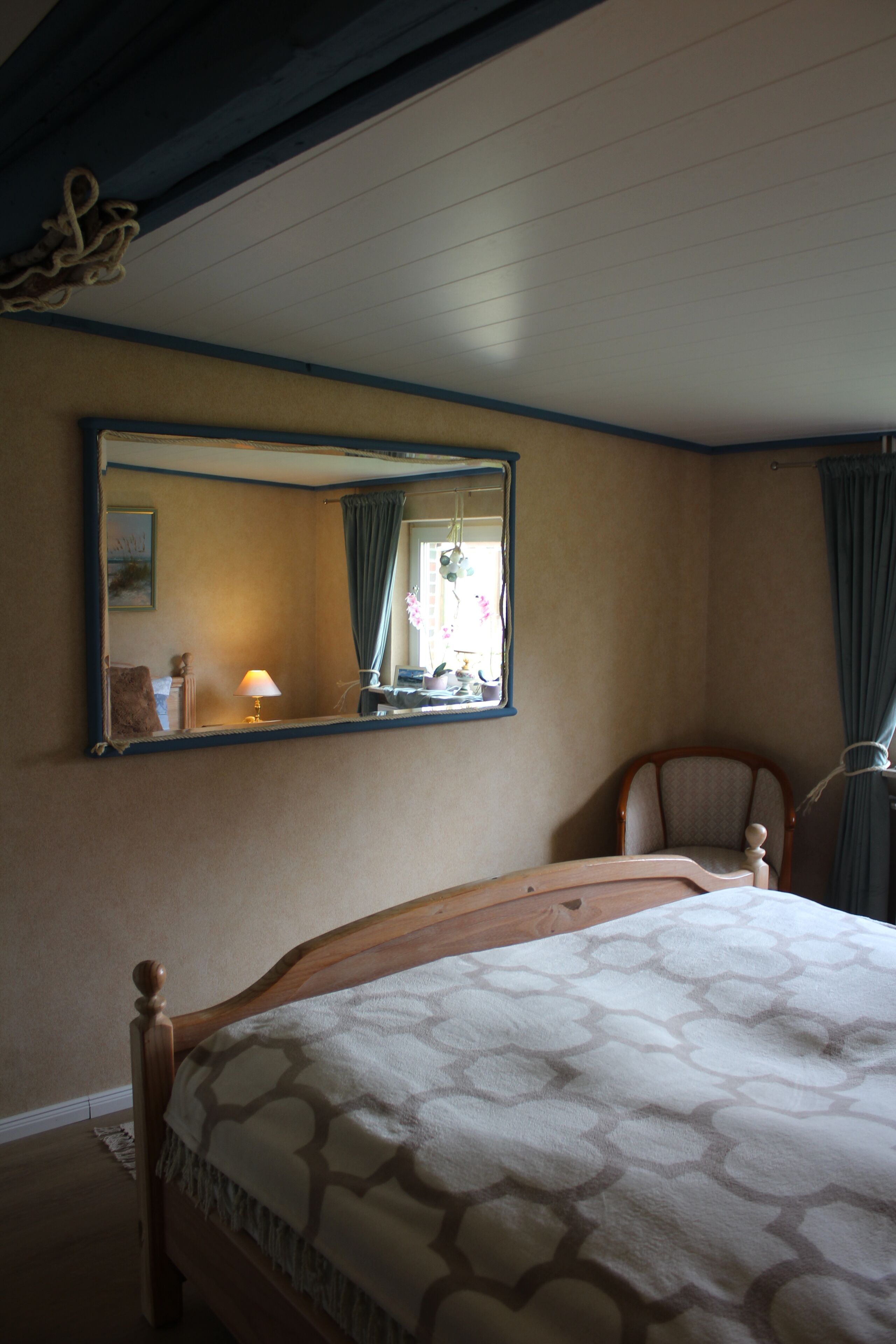 A bedroom with a wooden bed, a large mirror, and a chair.
