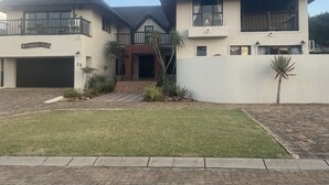 Une maison à deux étages avec un garage, un balcon et une pelouse bien entretenue.