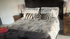 Un lit avec une literie à motifs, deux tables de chevet avec des lampes et un luminaire fixé au mur.