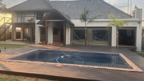 Une maison à deux étages dotée d’un patio couvert et d’une piscine.
