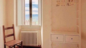 A room with a window overlooking a beach, a radiator, a wooden chair, and a white wardrobe with hanging space. - Double Rooms Mavitur Rooms (Assisi)