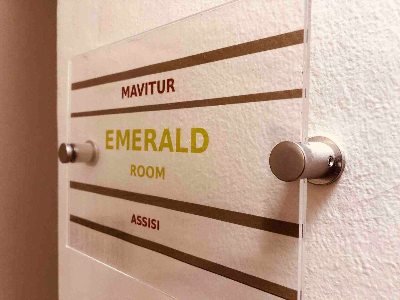 Una puerta con un letrero que indica 'EMERALD ROOM' y 'ASSISI' arriba.