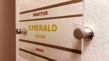 Una puerta con un letrero que indica 'EMERALD ROOM' y 'ASSISI' arriba.