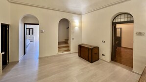 A spacious hallway with a wooden bench, a staircase, and an arched doorway leading to another room. - Double Room Mavitur Rooms (Assisi)