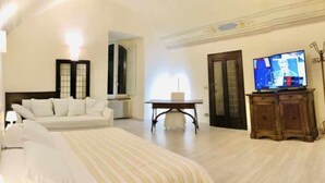 A hotel room with a bed, a sofa, a TV, a table, and a cabinet. - Double Room Mavitur Rooms (Assisi)
