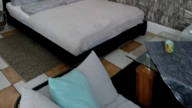 A bedroom with a bed, a small table, and a sofa.