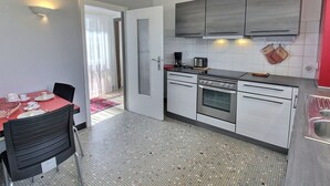 A compact kitchen with a dining area, featuring a small table with chairs, a coffee maker, and a toaster. - Spacious Apartment with Terrace & Garage, 10 Min Walk to Park in Colmar (Colmar)