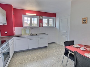 A compact kitchen with white cabinets, a red wall, and a tiled floor.