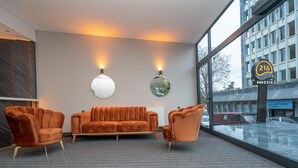 A modern lobby with a sofa and two armchairs, a large window with a view of the street, and a sign indicating '216 SUITES'. - Center Suite (Istanbul)