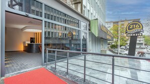 A hotel entrance with a red carpet, a glass door, and a sign indicating 216 suites. - Center Suite (Istanbul)