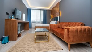 A modern hotel room with a wooden desk, a sofa, a bed, and a television. - Center Suite (Istanbul)