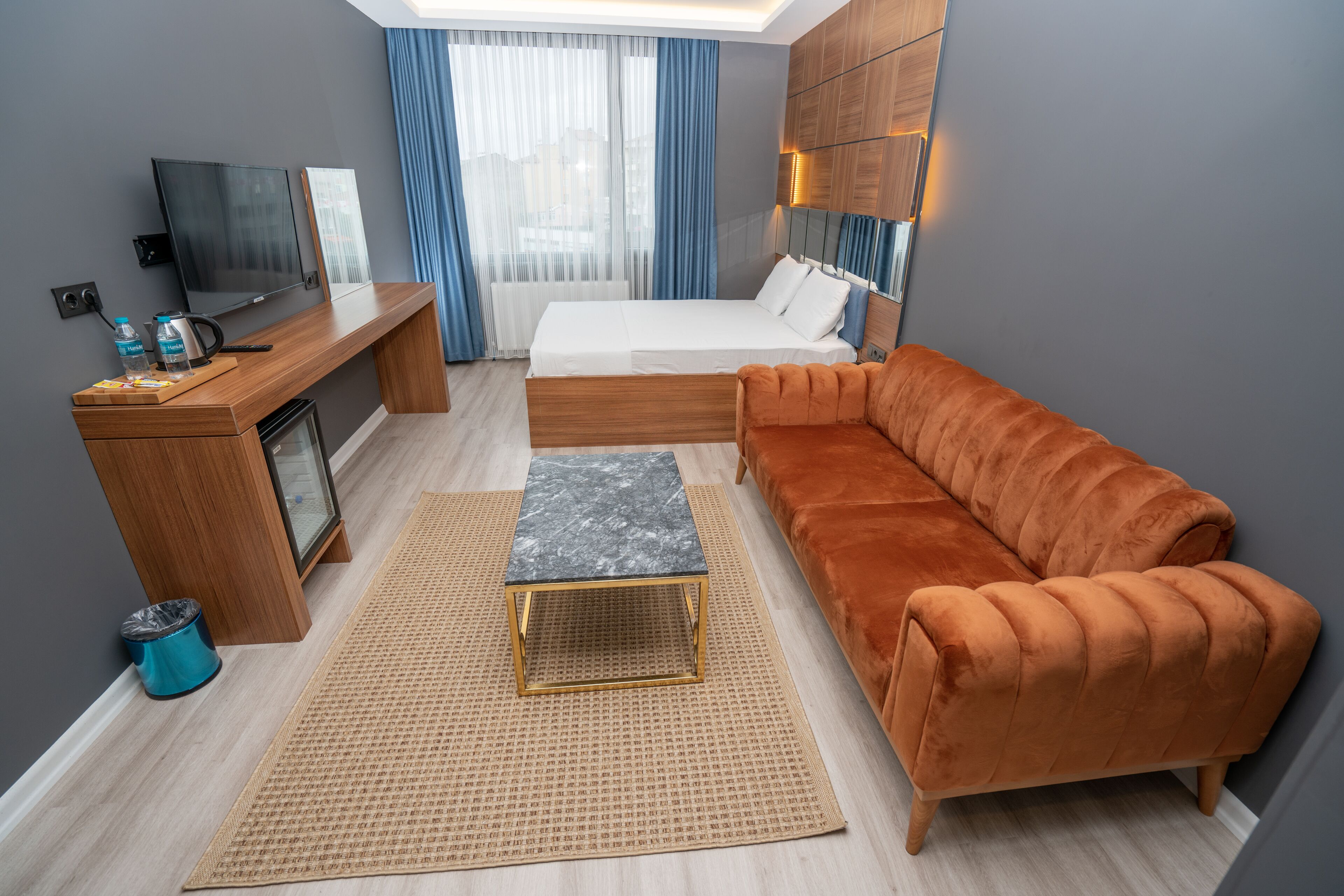 Ein modernes Hotelzimmer mit Bett, Sofa, Schreibtisch und Fernseher.