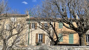 Un bâtiment traditionnel doté de nombreuses fenêtres et d’un mur de pierre en premier plan.